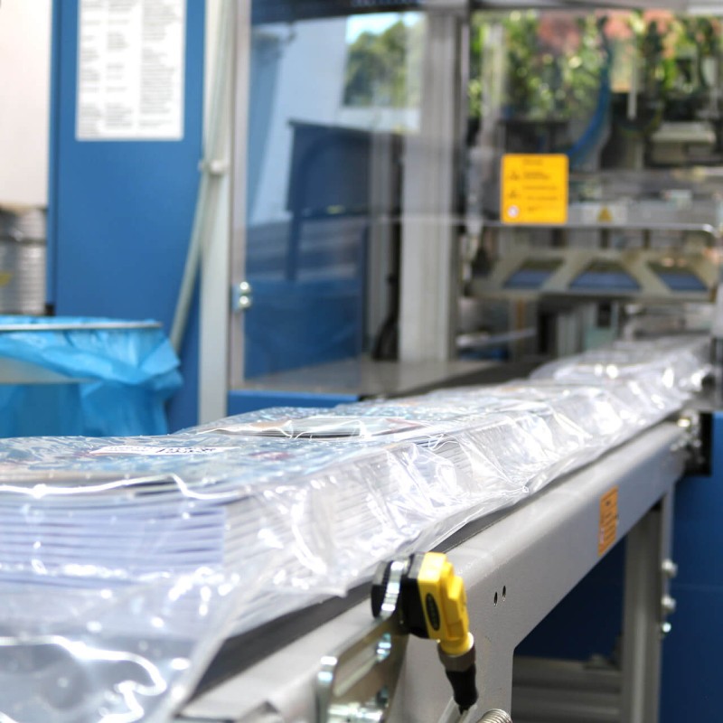 Fertig eingeschweißte und mit Label versehene Beipacks / Zubehörbeutel auf dem Weg zum Verpacken
